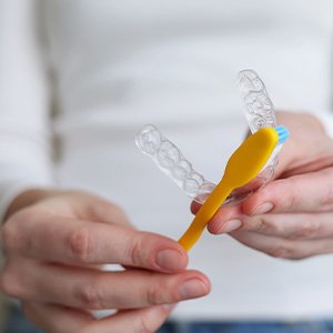 Patient using toothbrush to clean aligners
