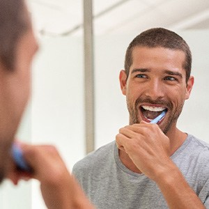 Dallas patient brushing teeth with fluoride toothpaste 